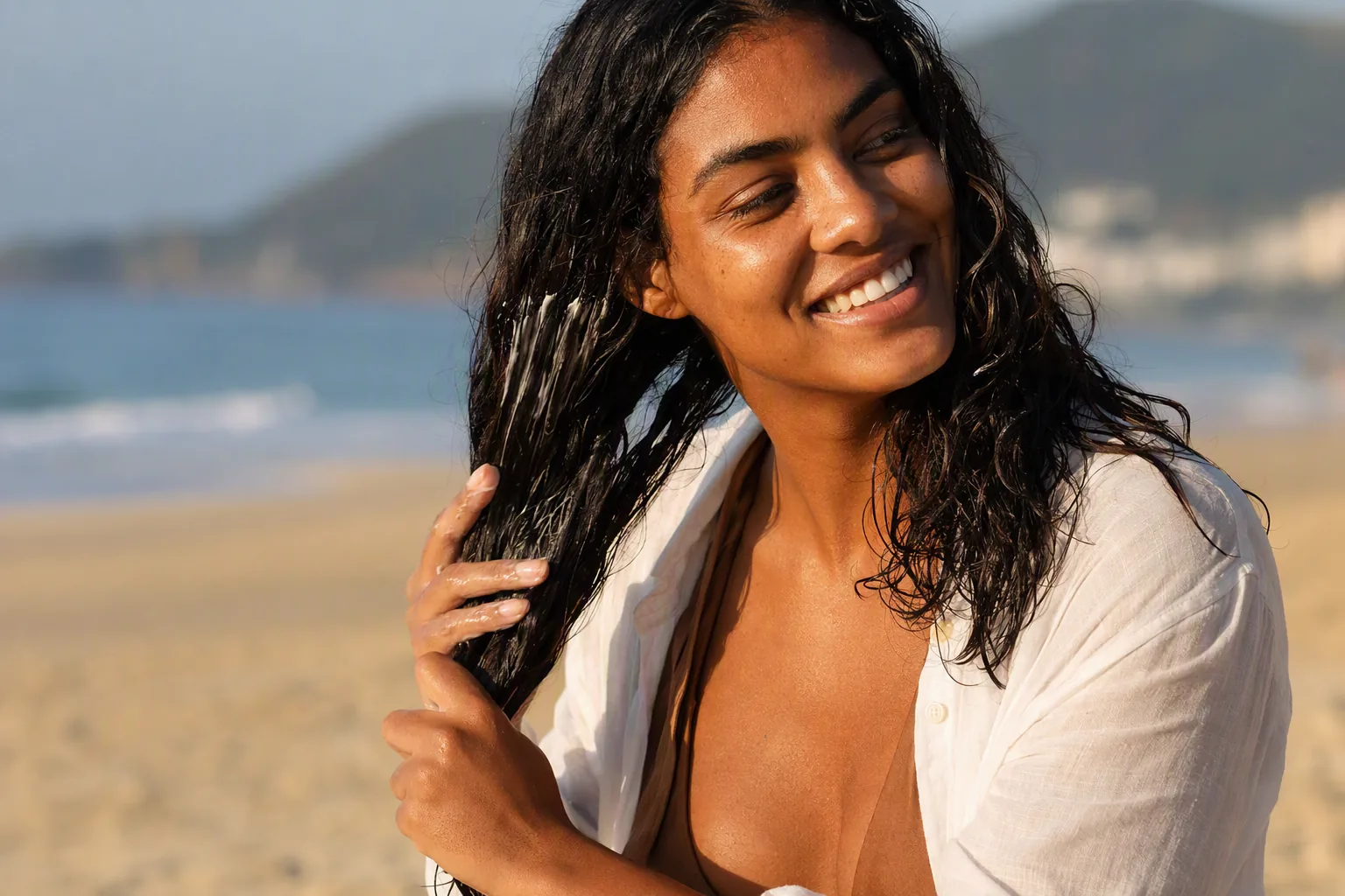 Mulher na praia ao fim da tarde passando creme sem enxágue nas ondas úmidas de sal
