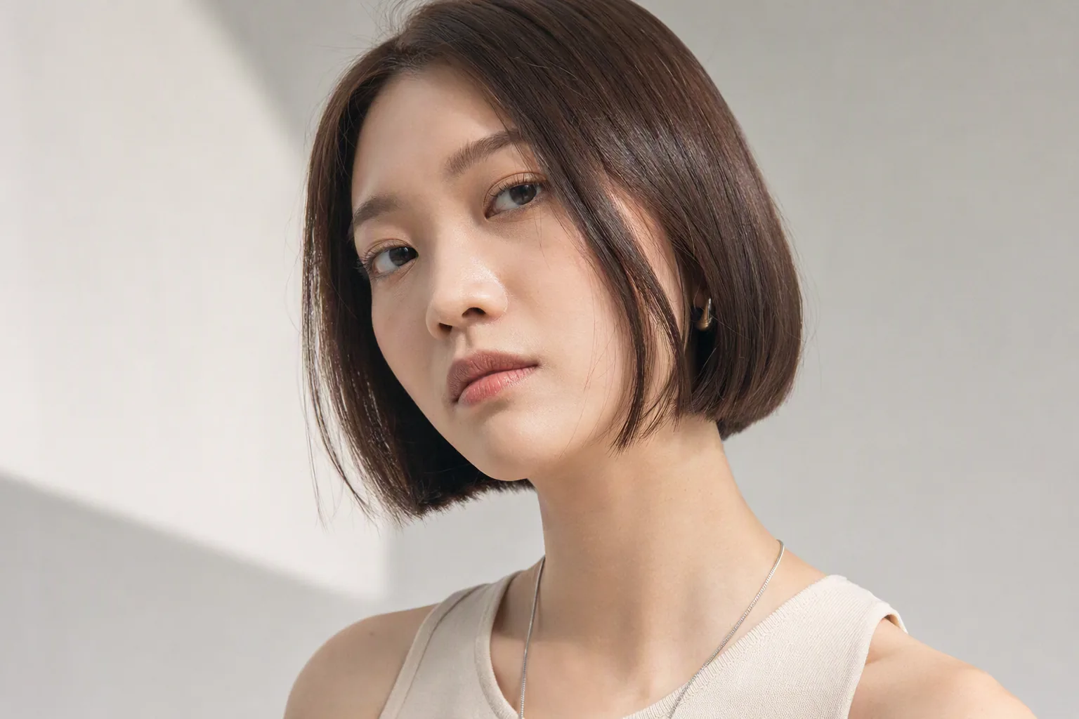 齊下巴短髮女生正面對鏡頭，露出臉型線條，米色背景