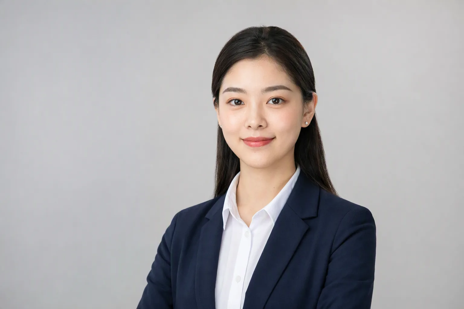 女性求職大頭照:深藍西裝外套搭白襯衫,頭髮整齊收攏,淺灰背景棚拍